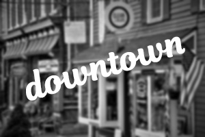 "downtown" in white script font over blurry black and white picture of store fronts near homes for sale in Manasquan NJ