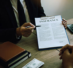 Insurance provider holding clipboard with paper titled INSURANCE out to business owner to review and ensure fire alarm service in NJ